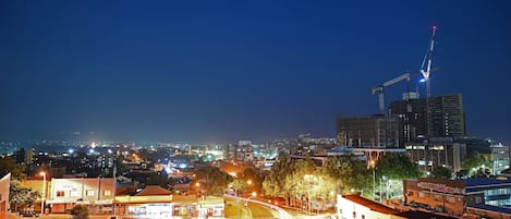 A nighttime cityscape with illuminated streets, buildings, and a construction crane.