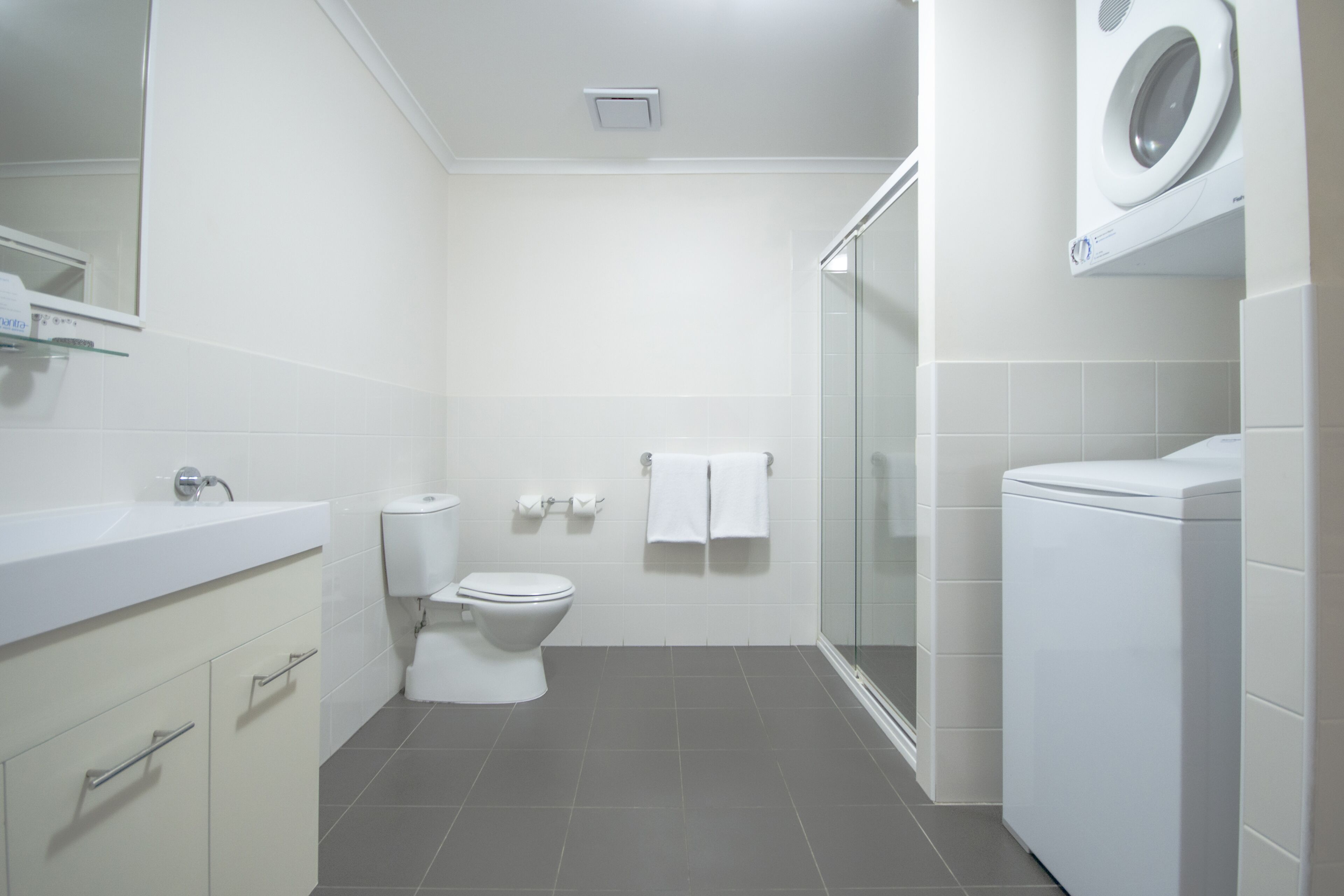 A modern bathroom with a sink, toilet, and washing machine.