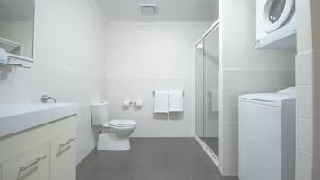 A modern bathroom with a sink, toilet, and washing machine.