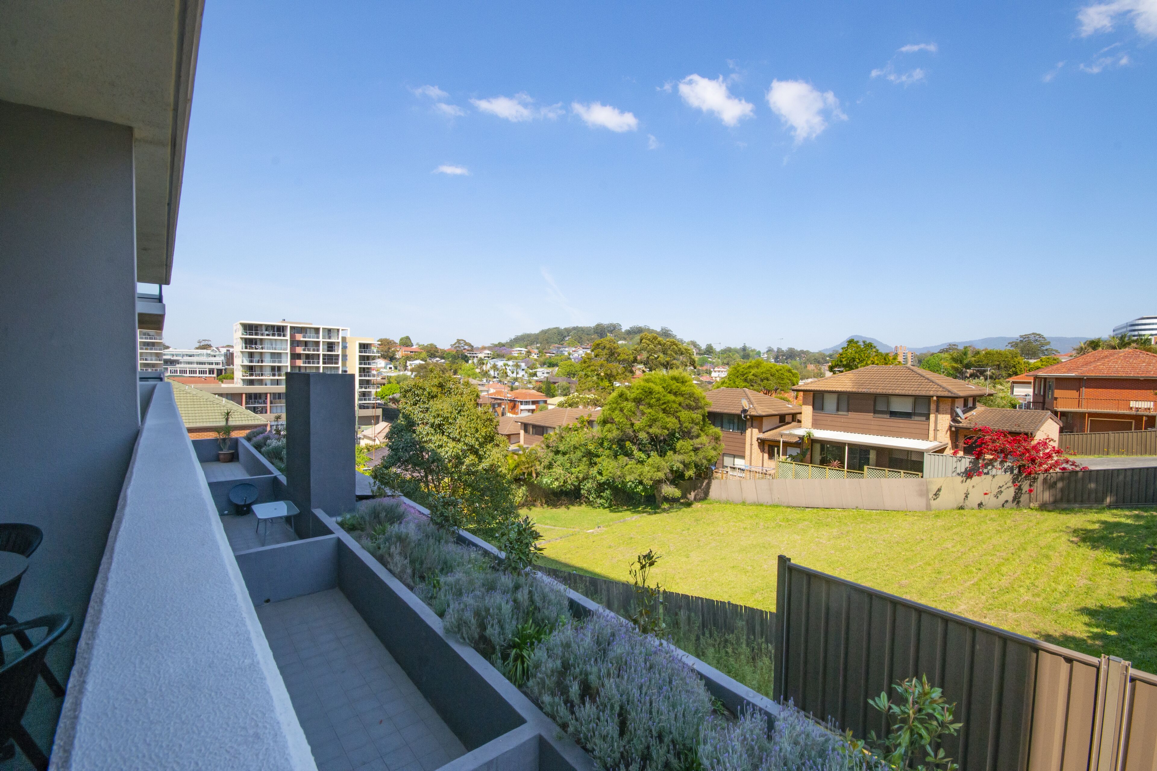 A balcony with a view of a residential area, including houses and greenery.