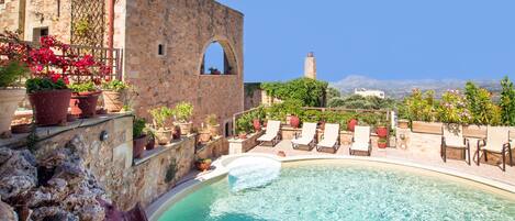 Een buitenzwembad, parasols bij het zwembad en ligstoelen