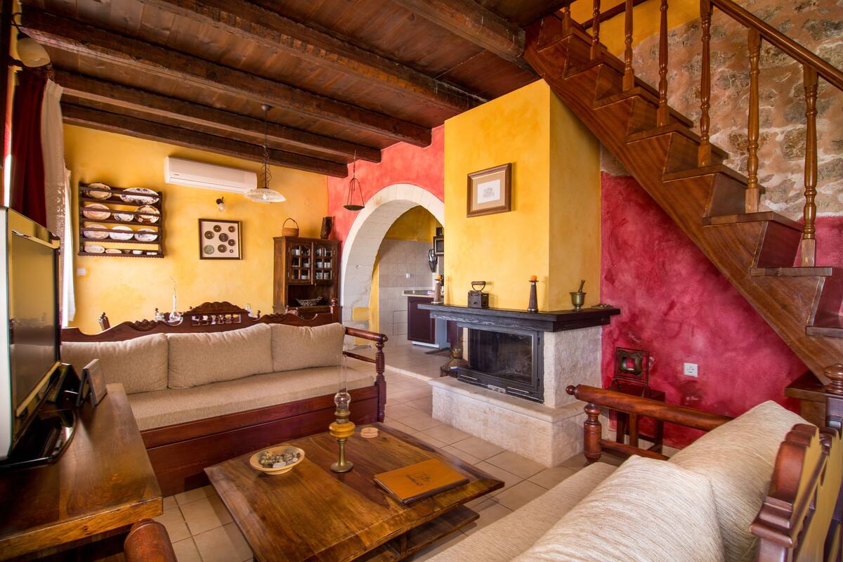 A cozy living room with a wooden staircase, a fireplace, and a sofa.