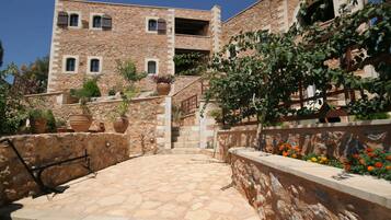 A stone building with a courtyard, potted plants, and a staircase leading to an upper level.