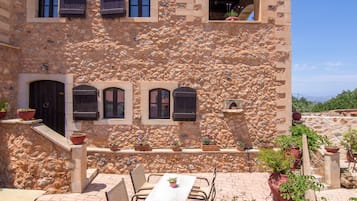 A stone building with a terrace, outdoor seating, and potted plants.
