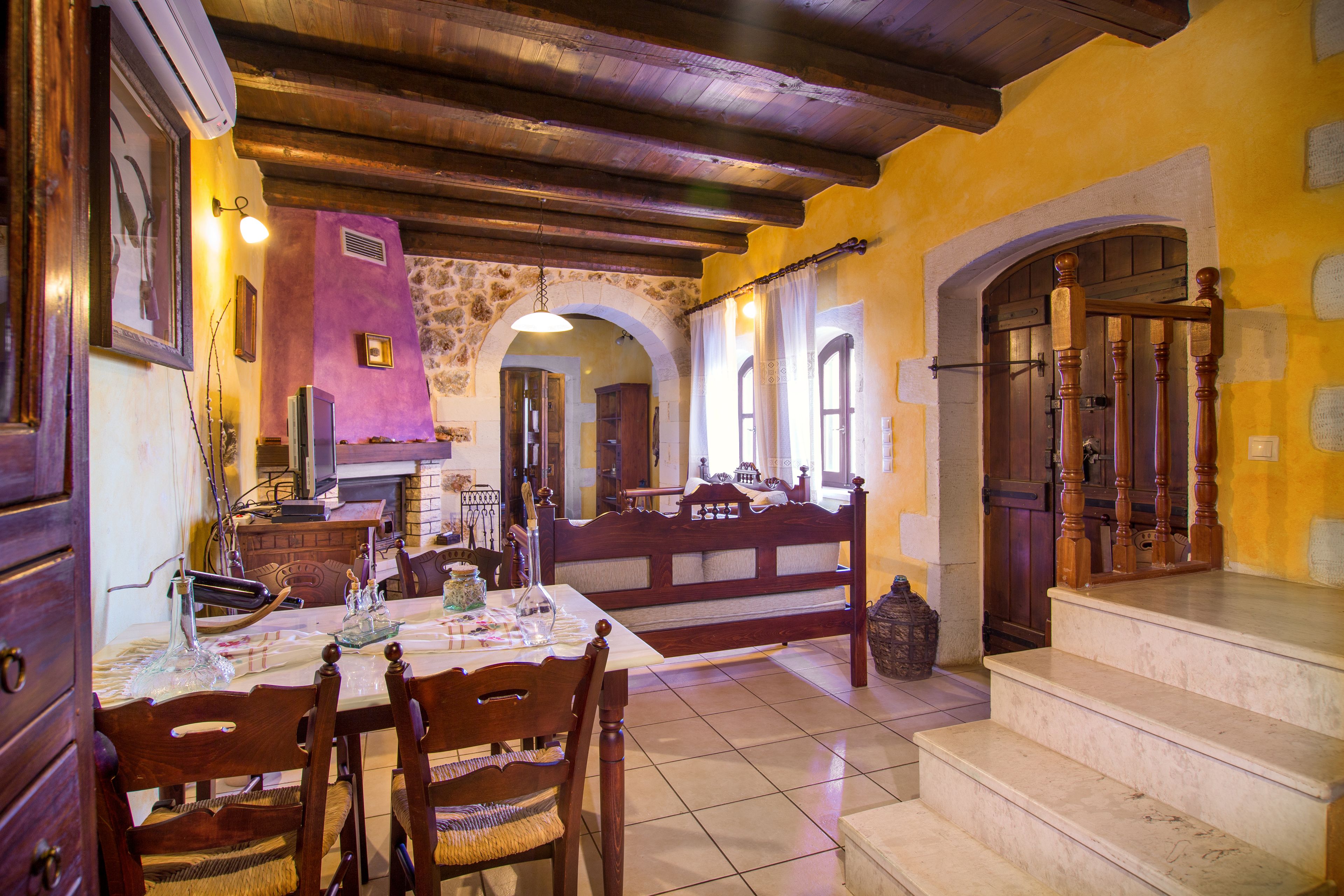 A traditional dining area with a wooden table, chairs, and a stone wall.