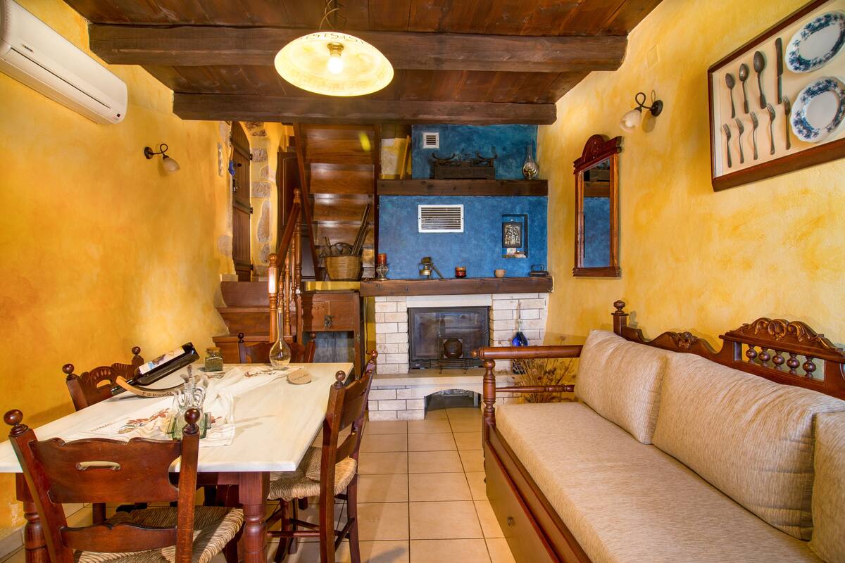 A dining area with a wooden table and chairs, a fireplace, and a sofa.