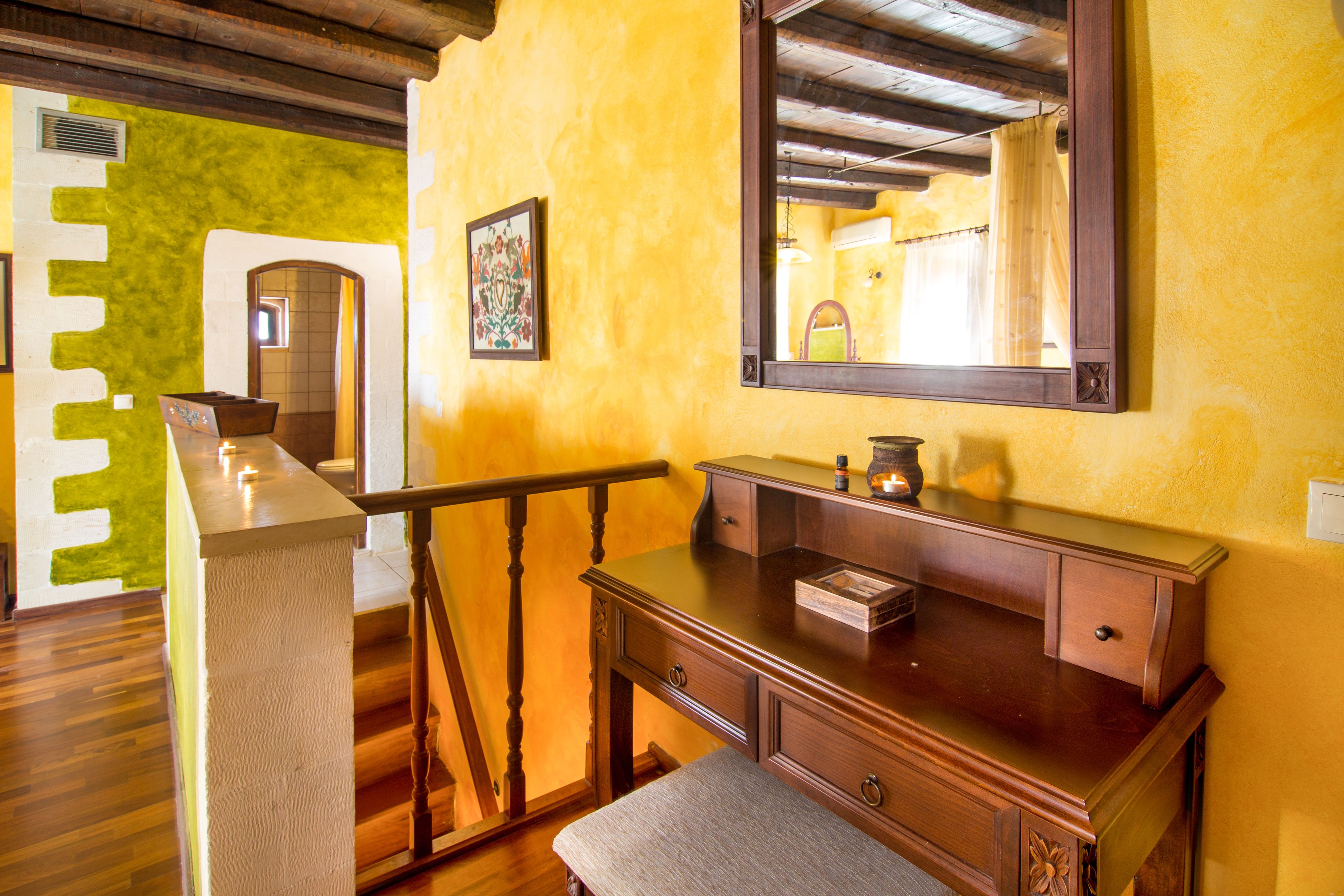 A wooden dresser with drawers and a mirror, a bench, and a small table with a candle.