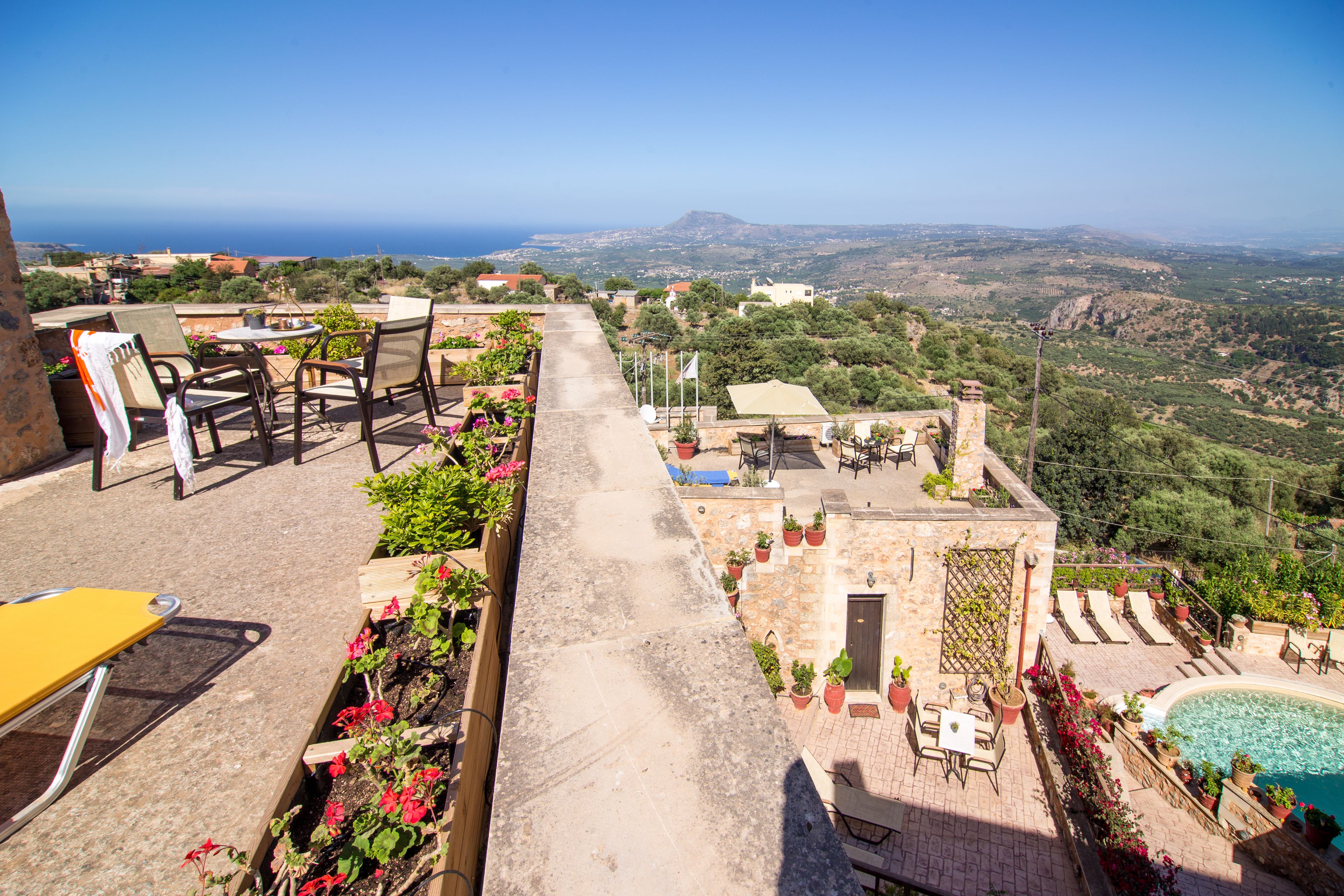 A rooftop terrace with outdoor seating, a pool, and a view of the landscape.