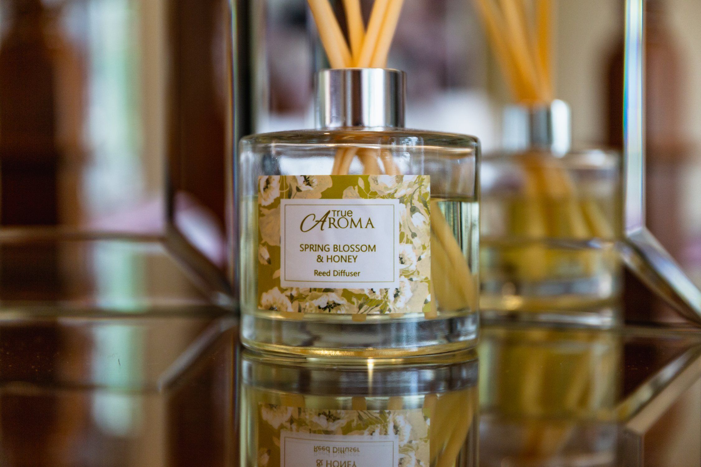 A glass bottle of True Aroma Spring Blossom & Honey reed diffuser.