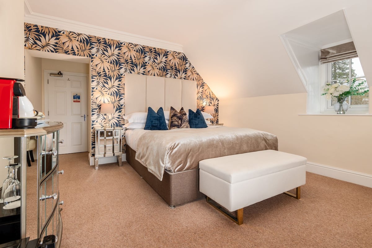 A bedroom with a bed, bedside tables, a bench, a wardrobe, and a window with a view.