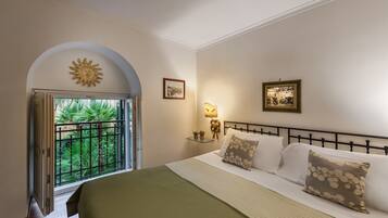 A bedroom with a bed, a nightstand, a lamp, and a window with a view of greenery.
