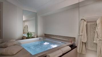 Ein modernes Badezimmer mit einer großen Badewanne, einem Spiegel und Handtüchern.