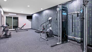 A gym with various exercise equipment, including a treadmill, elliptical, and weight machines.