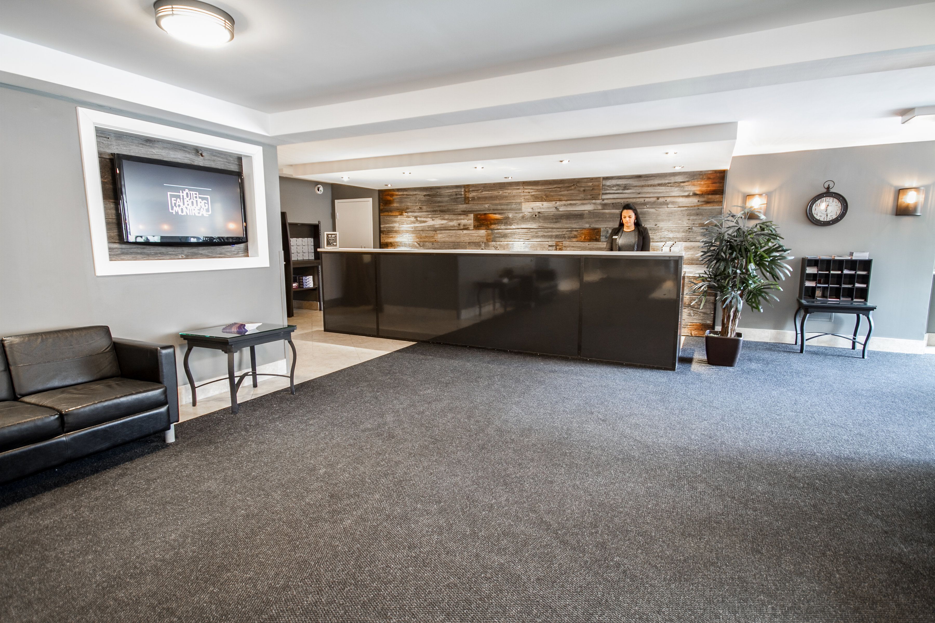 Un lobby moderno de hotel con una recepción, un televisor de pantalla plana, un sofá y una mesa de centro.
