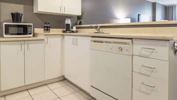 A modern kitchen with white cabinetry, a microwave, a coffee maker, and a dishwasher.