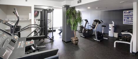 Une salle de sport équipée de tapis de course, de vélos elliptiques et de matériel de musculation.