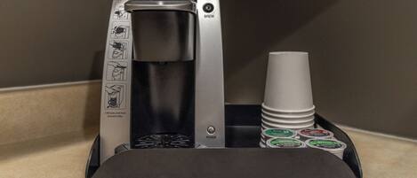 A Keurig coffee machine with a drip tray holding coffee pods and a disposable cup.