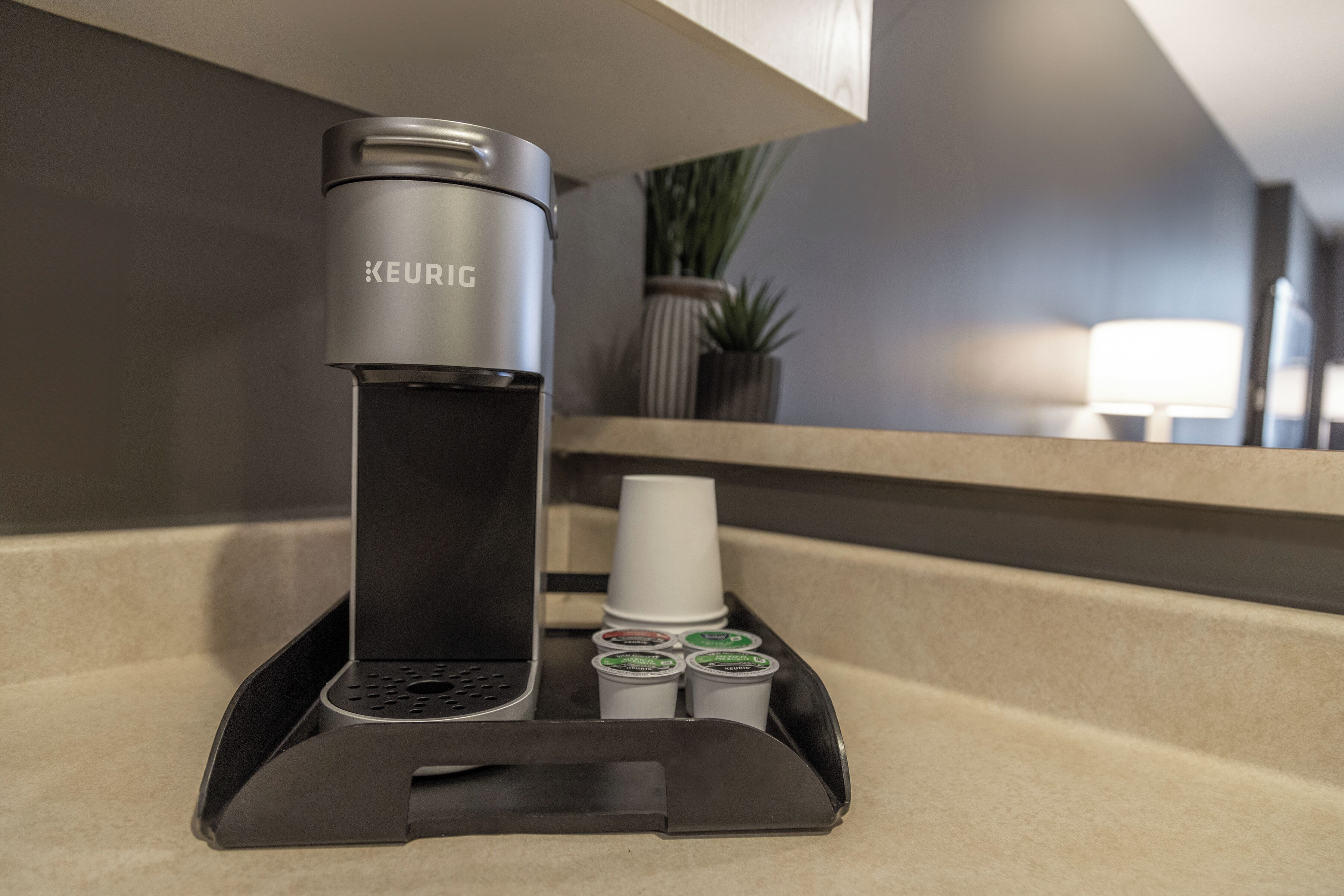 A Keurig coffee machine on a countertop with disposable cups and coffee pods.