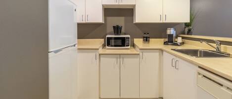 A modern kitchen with white cabinets, a microwave, a coffee maker, and a sink.