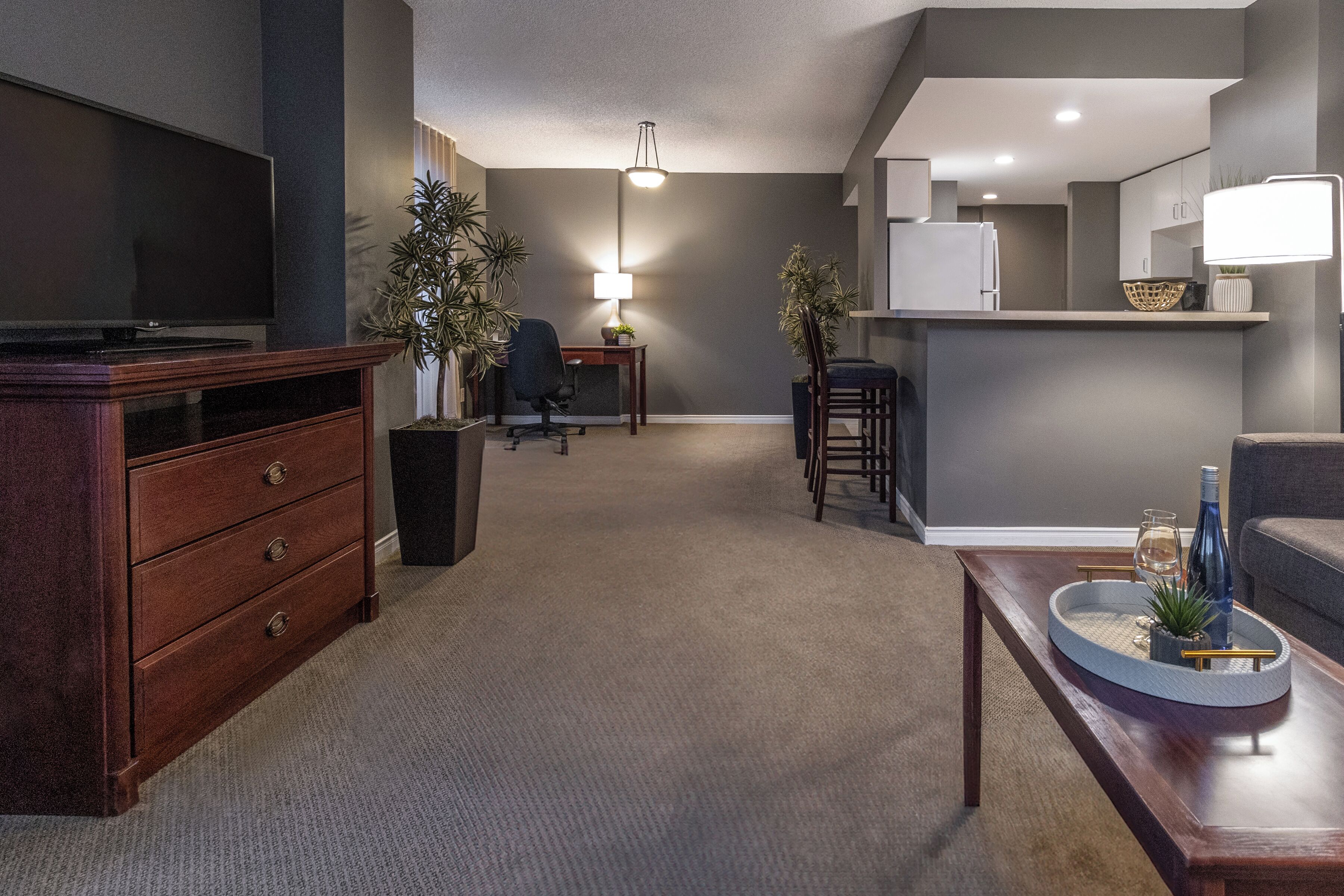 Een moderne woonkamer met een flatscreen televisie, een houten kast en een salontafel met decoratieve objecten.