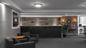 A modern hotel lobby with a reception desk, seating area, and a clock on the wall.