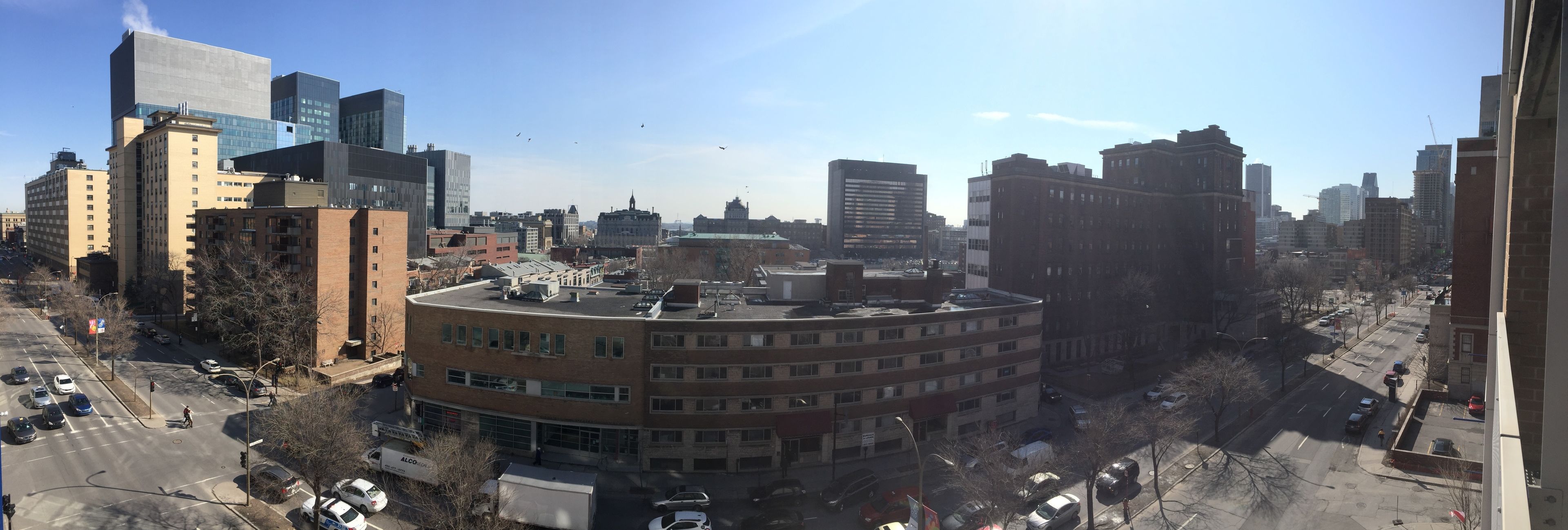En stadsbild med olika typer av byggnader, inklusive en framträdande, cirkelformad byggnad med flera våningar och ett platt tak.