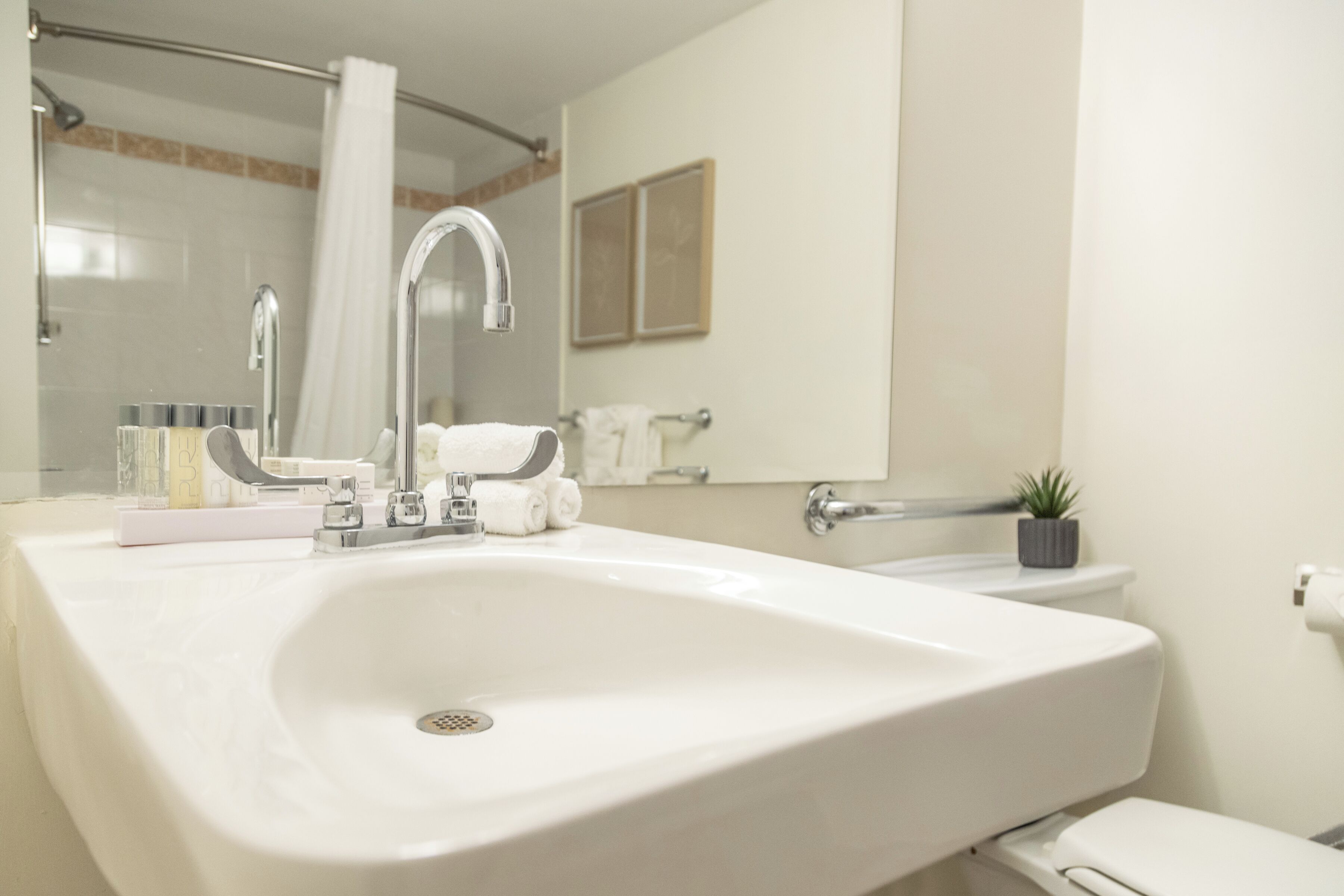 Een badkamer met een wit wastafelmeubel, een spiegel, een handdoekrek en een toilet.