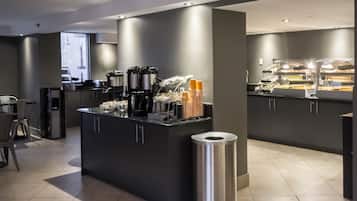 Un área de cocina moderna con una isla central, máquinas de café y un cubo de basura.