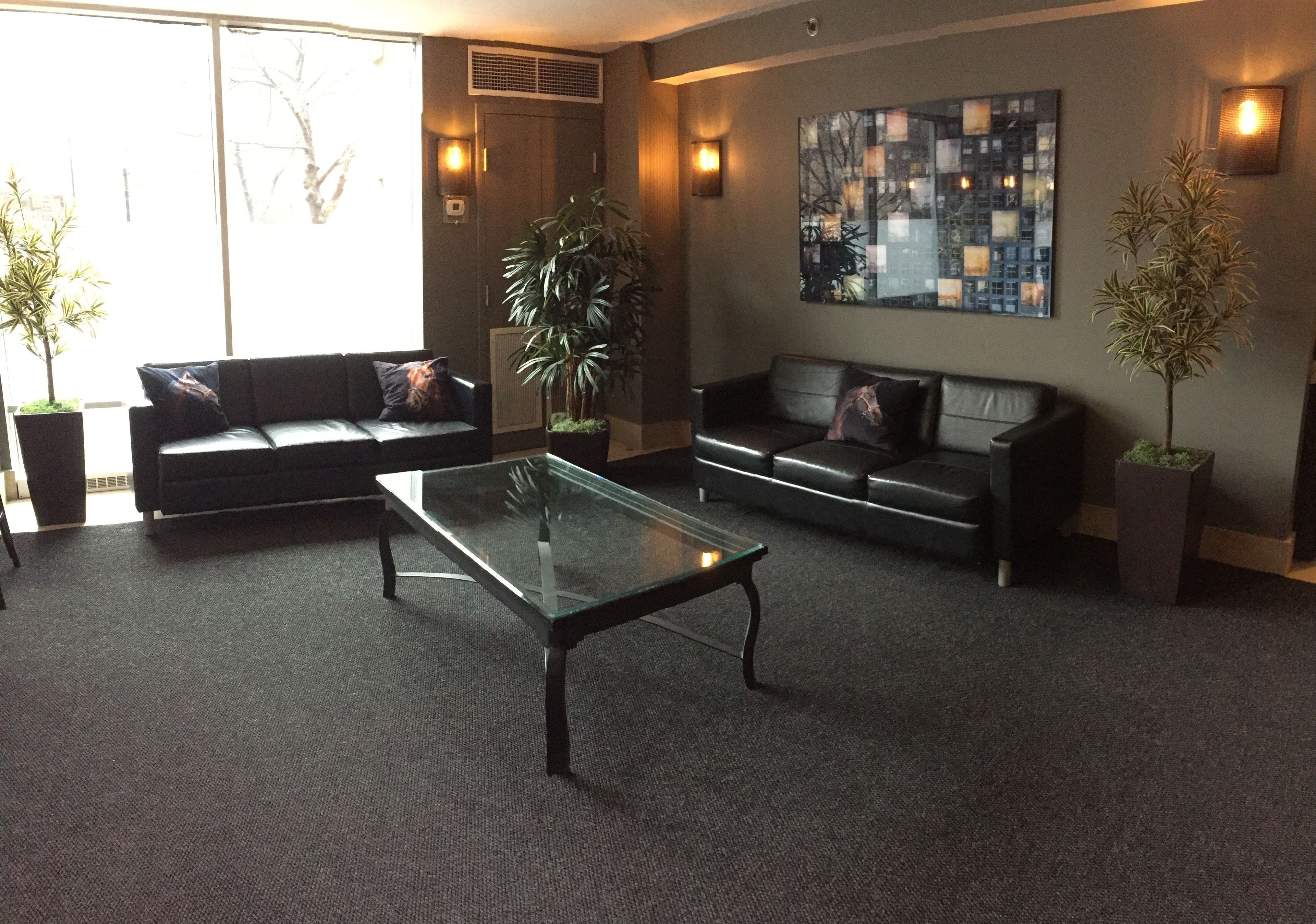 Eine moderne Lobby mit zwei Sofas, einem Glastisch und Blumentöpfen.