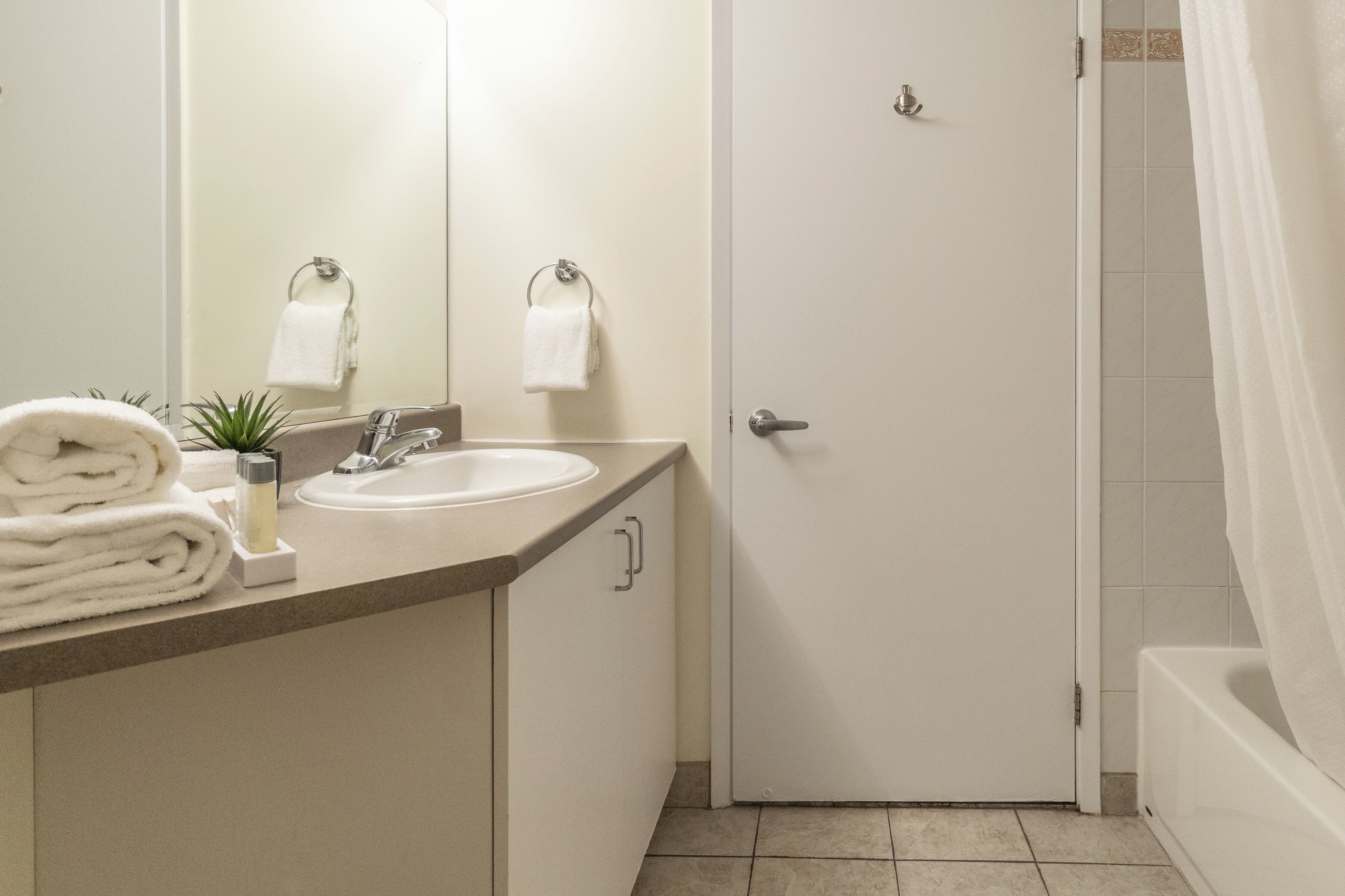 Un baño con un lavamanos blanco, un dispensador de toallas y una puerta que da a la zona de la ducha.