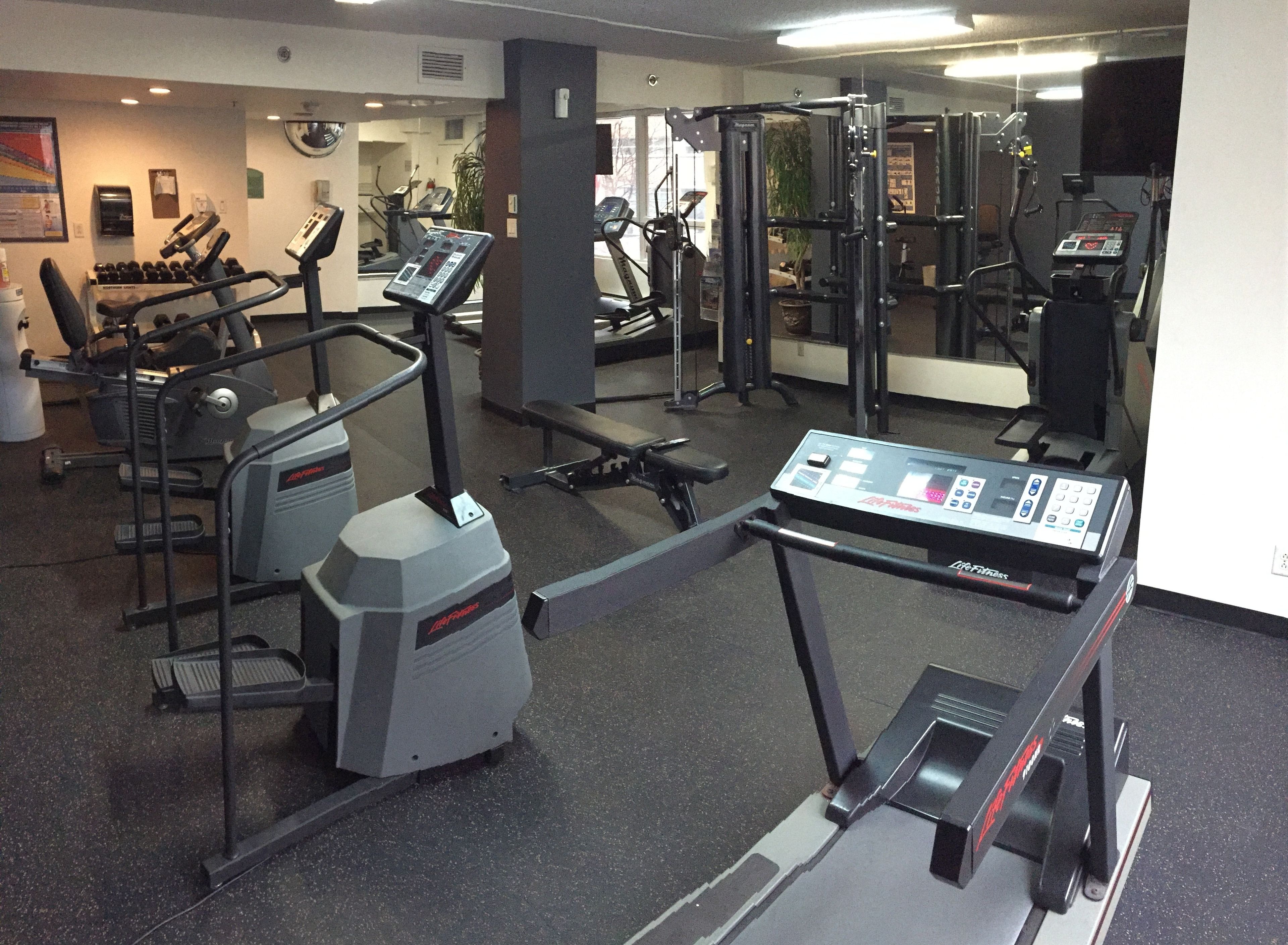 Un gimnasio con cintas de correr, máquinas elípticas y equipo de levantamiento de pesas.