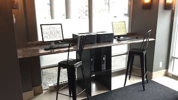 A hotel reception desk with two computer stations, a black chair, and a sign indicating the hotel name.