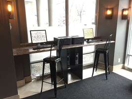 A hotel reception desk with two computer stations, a black chair, and a sign indicating the hotel name.