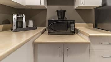 Une cuisine équipée d’un four à micro-ondes, d’une machine à café et d’une casserole posée sur le plan de travail.