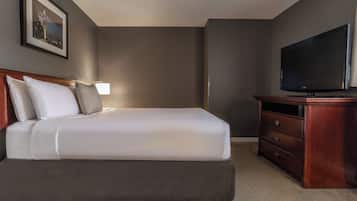 Habitación de hotel con cama, televisión, cómoda y un cuadro en la pared.