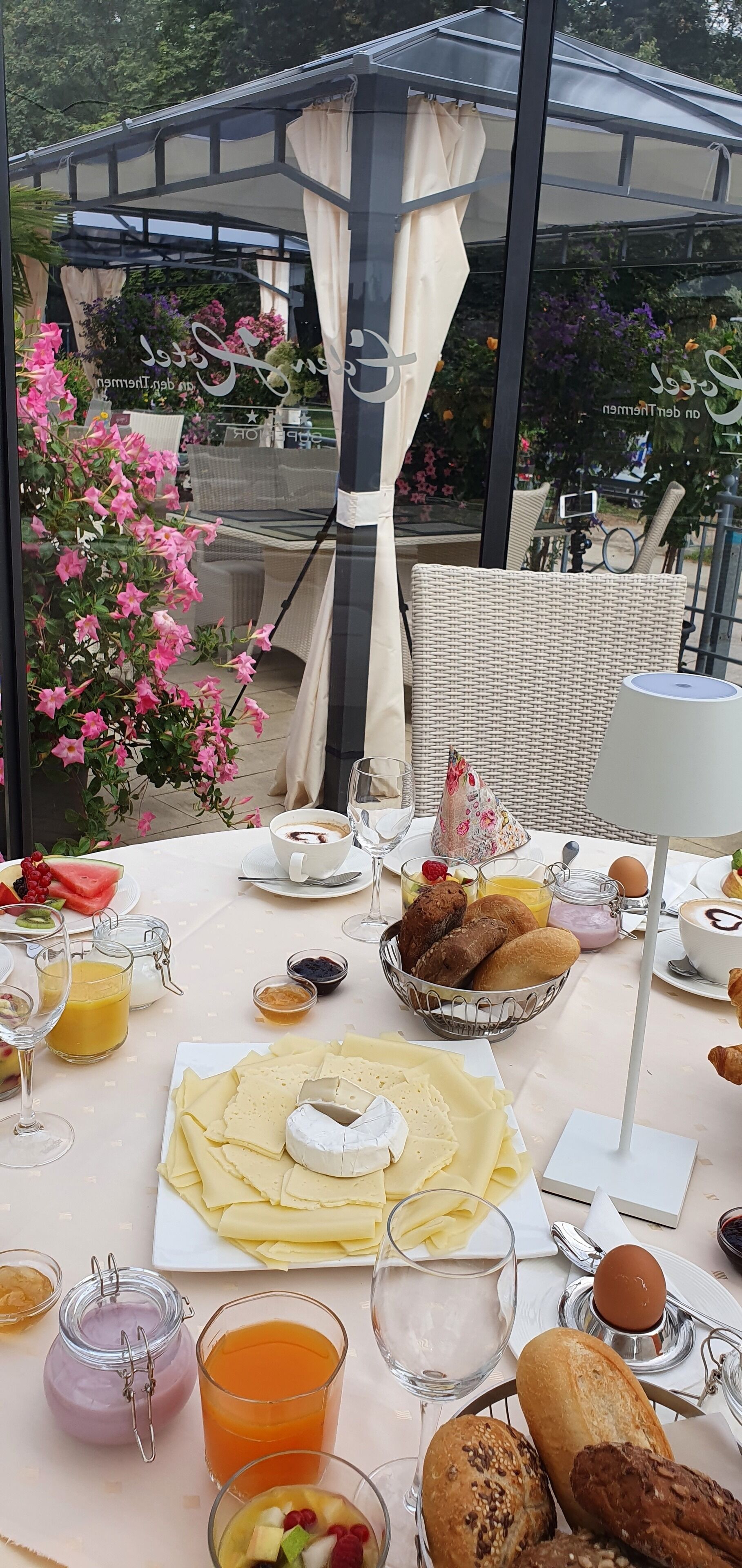 Ein Essbereich im Freien mit einem Tisch, gedeckt für das Frühstück, einschließlich Brot, Käse und Obst.