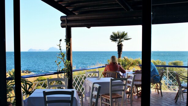 An outdoor dining area with tables and chairs, overlooking the sea. - Hotel Puntaquattroventi (Ercolano)