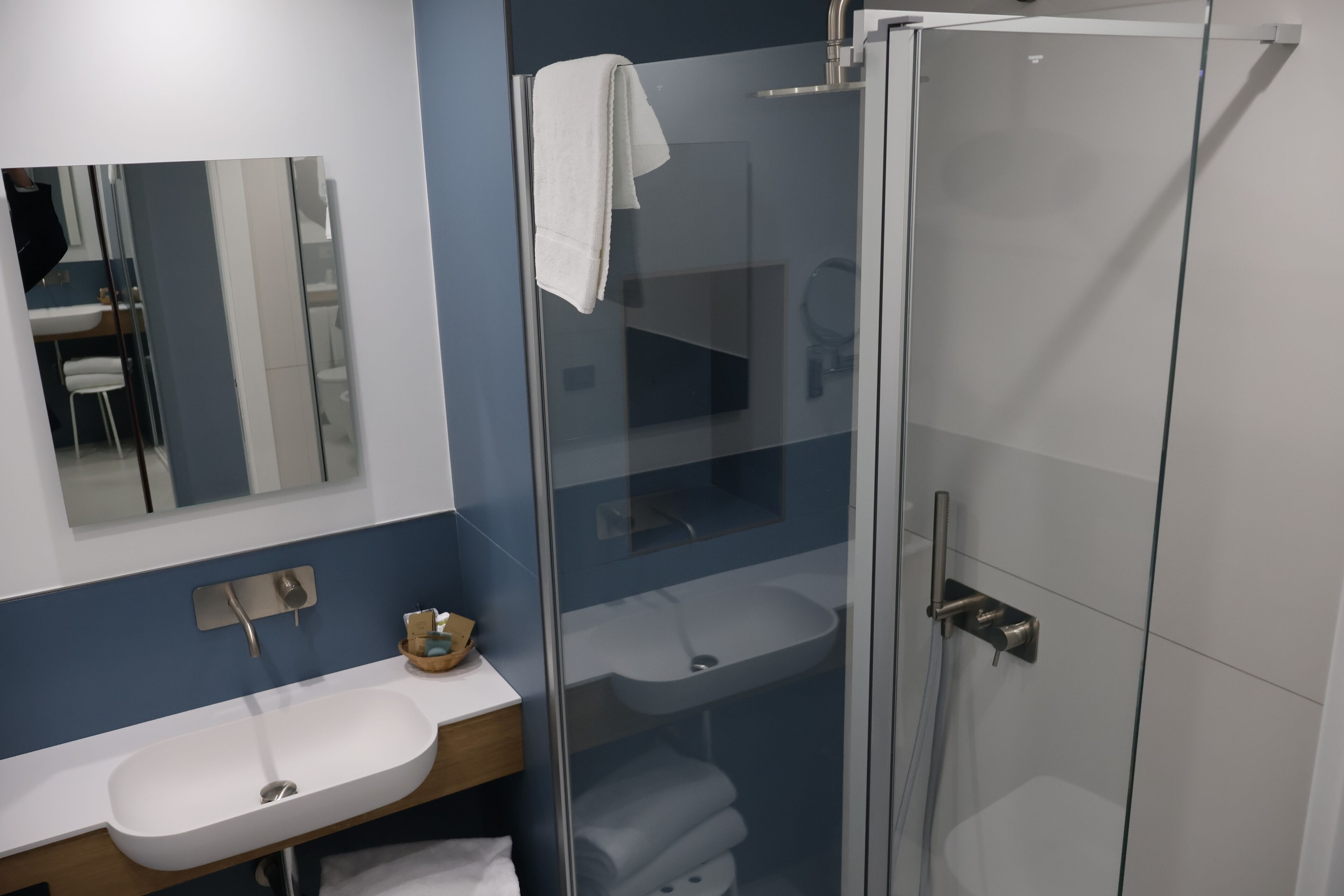 A modern bathroom with a glass-enclosed shower, a white sink, and a mirror above the sink.