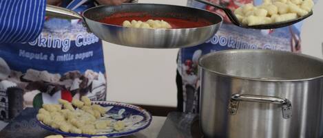 Una persona cocinando ñoquis en una sartén sobre la hornilla.