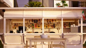 A bar area with shelves of bottles and glasses, a cash register, and a small table. - Hotel Puntaquattroventi (Ercolano)