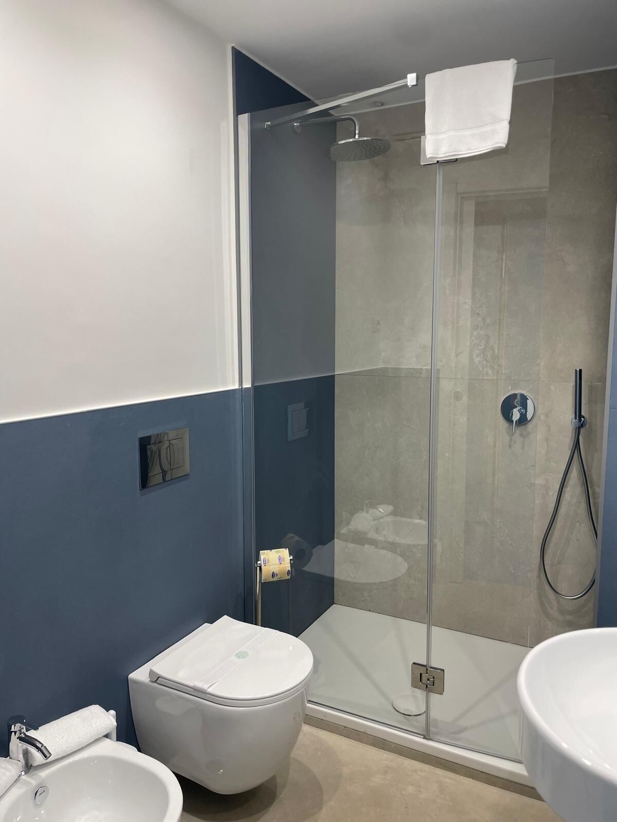 A modern bathroom with a glass-enclosed shower, a white toilet, and a sink.
