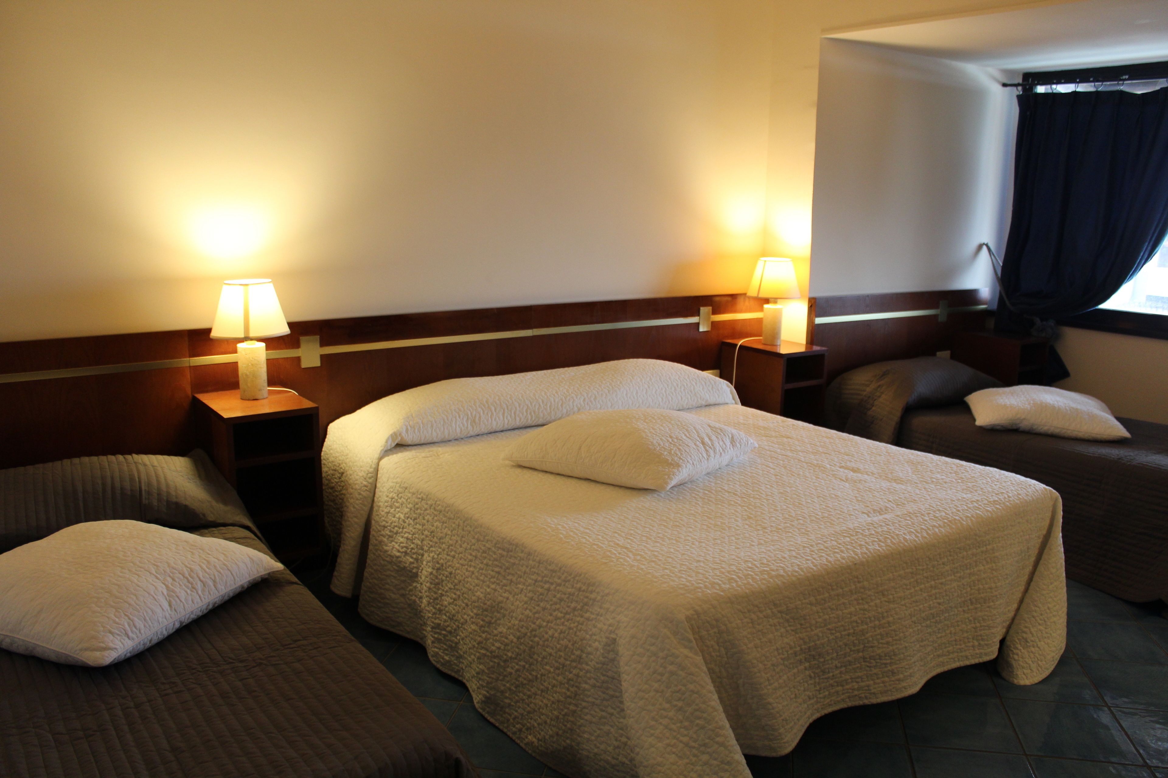 A hotel room with two single beds, a sofa, and two bedside lamps.