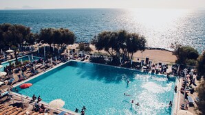 A swimming pool with lounge chairs and umbrellas, surrounded by trees and a beach. - Hotel Puntaquattroventi (Ercolano)