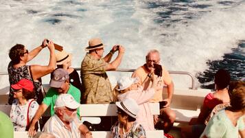 A boat with passengers enjoying the view of rocky cliffs and the sea.