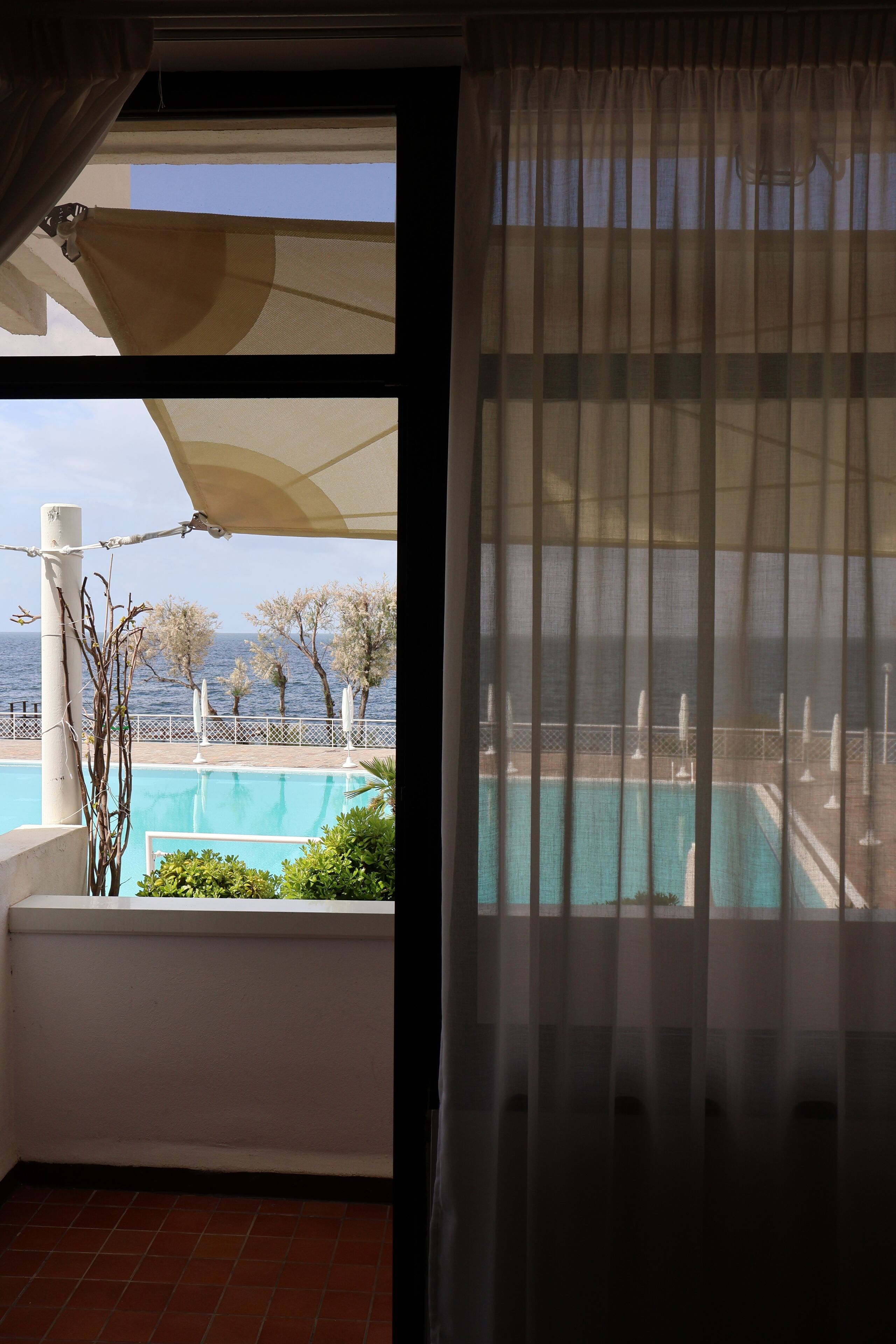 Un balcone con piscina, vista sul mare e ringhiera bianca.