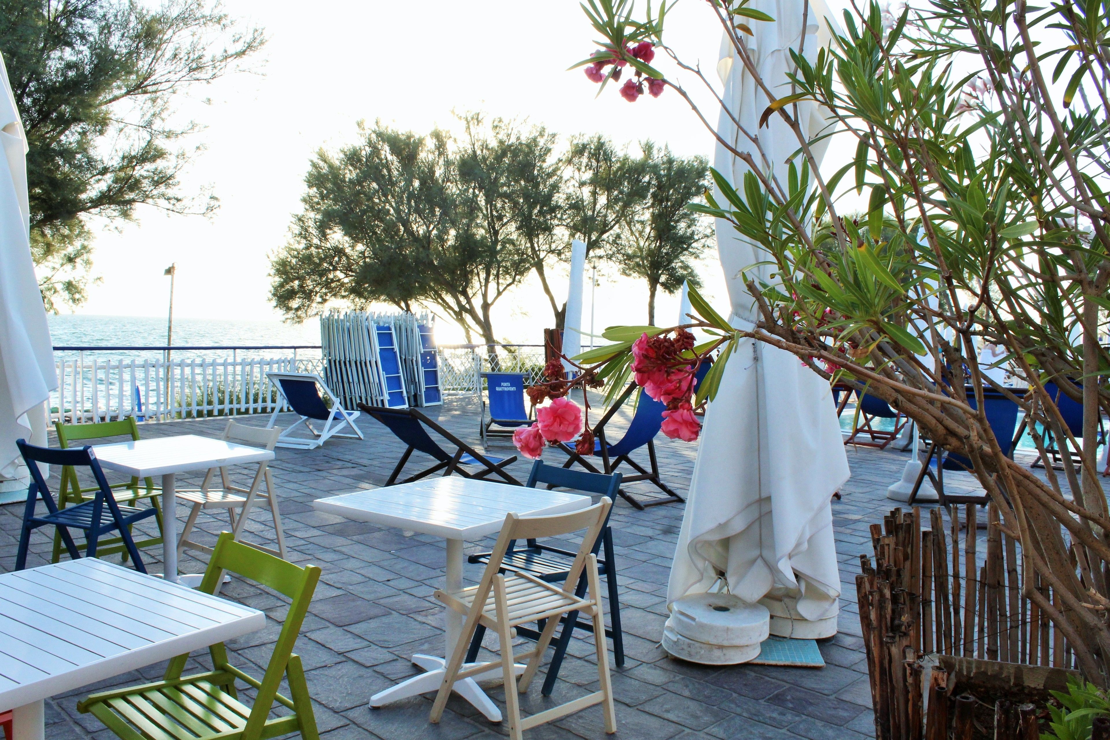 An outdoor patio with tables and chairs, overlooking the sea.