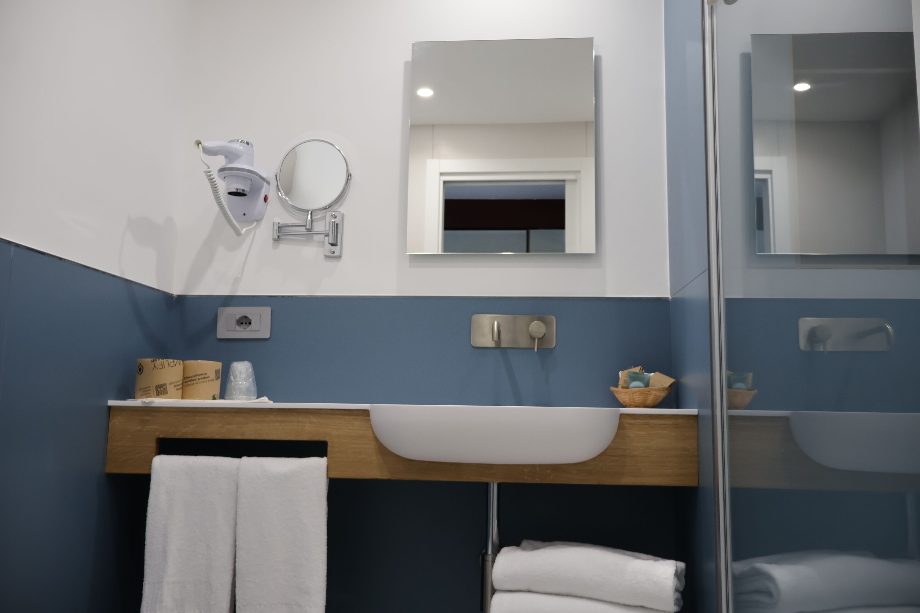 A bathroom with a white sink, a mirror, a towel rack, and a shower area.