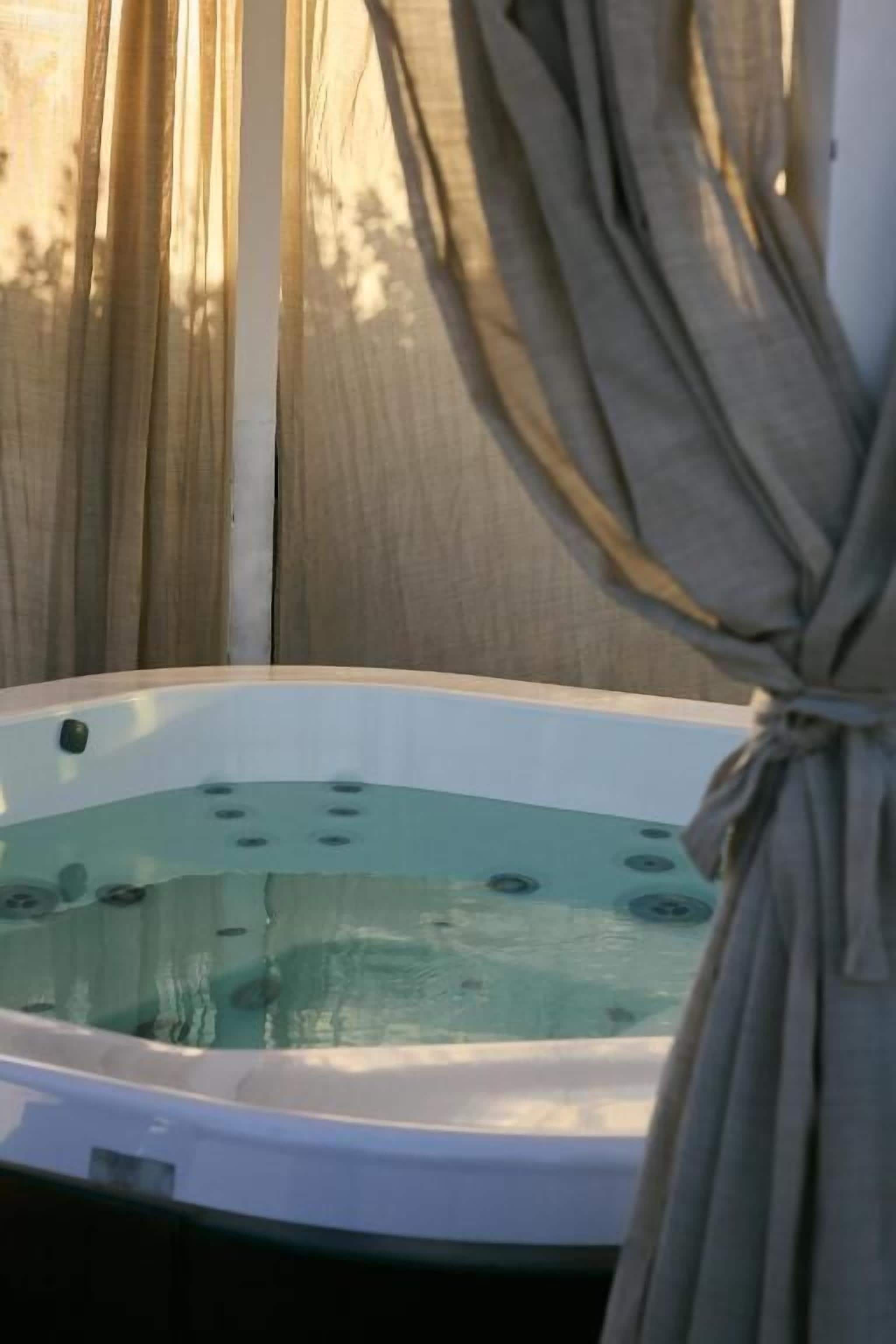 Un bain à remous avec vue sur une clôture en bois et une fenêtre.