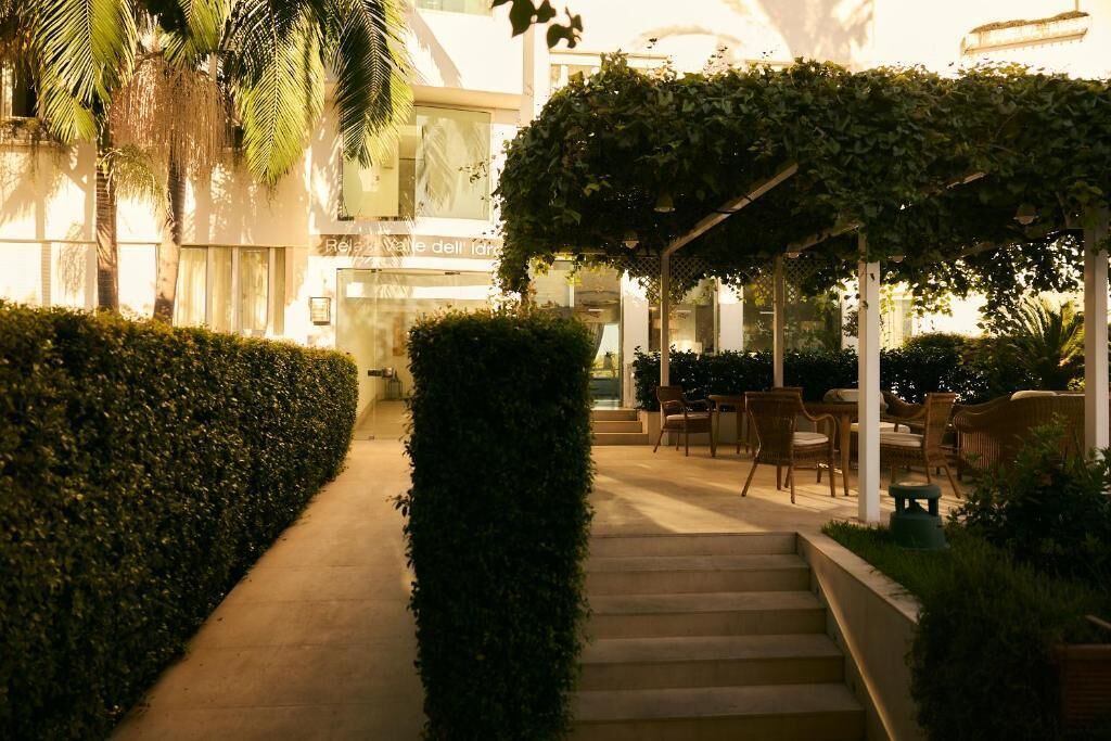 A well-lit outdoor area with a pathway leading to a covered seating area with chairs and tables.