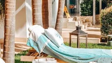 A hammock lounge area with a wicker table, a glass of drink, and a sign reading "RELAIS VALLE DELL'ORO OTRANTO".